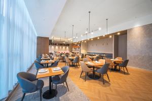 a restaurant with tables and chairs and a cafeteria at Kyriad Hotel Kunming Xishan Wanda Plaza Railway Station in Kunming