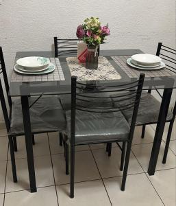 a black table with chairs and a vase of flowers at Pequeño apartamento Aeropuerto CDMX in Mexico City