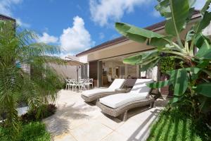 a patio with two lounge chairs and a table at VILLA LILOU, Splendide villa au centre de Grand Baie in Grand Baie
