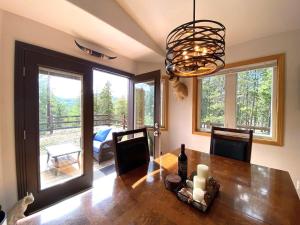 a dining room with a wooden table and a chandelier at Echo Hills Mountain Lodge - Evergreen Mountain Top Retreat - 15 minutes to SKI!! in Evergreen