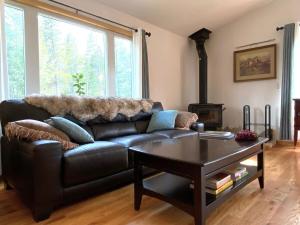 a black leather couch in a living room with a table at Echo Hills Mountain Lodge - Evergreen Mountain Top Retreat - Foothills of the Rockies in Evergreen