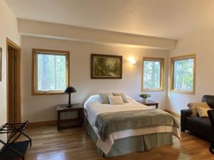 a bedroom with a bed and a couch and windows at Echo Hills Mountain Lodge - Evergreen Mountain Top Retreat - 15 minutes to SKI!! in Evergreen
