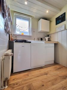 a small kitchen with white cabinets and a window at Mien lüttes Glück -Fewo Backboord in Zempin