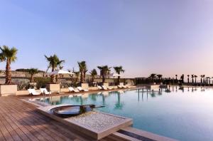 a large swimming pool with chairs and palm trees at Hyatt Regency Istanbul Atakoy in Istanbul