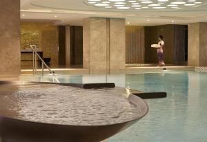 a woman standing next to a swimming pool in a building at Hyatt Regency Istanbul Atakoy in Istanbul