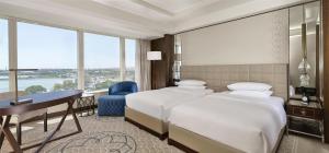 a hotel room with two beds and a desk and windows at Hyatt Regency Istanbul Atakoy in Istanbul