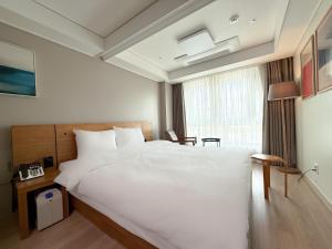 una camera da letto con un grande letto bianco e una finestra di Sokcho Marina Hotel a Sokcho