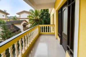 a balcony of a house with yellow railing and palm trees at Sonikas Holiday Homes (Studio) in Candolim