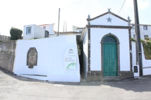 a white building with a green door on a street at Aldeia do Priolo in Nordeste