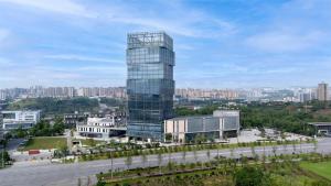 广安市广安希尔顿逸林酒店的一座高大的玻璃建筑,以城市为背景