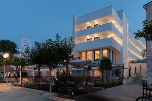 普莱克Hotel Preko Ugljan Island, Curio Collection By Hilton的前面有桌子和伞的建筑