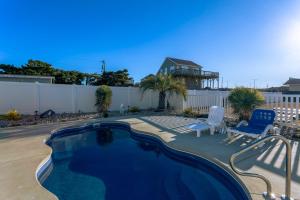 a swimming pool in a yard with two chairs and a fence at 5062 - Our Bright Idea in Kill Devil Hills
