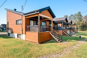 a house with a large deck on a yard at Ski and Spa - L'Altitude des Sommets in Stoneham