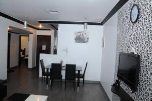 uma sala de jantar com mesa e cadeiras e uma televisão em Arinza Tower Quality Apartments em Kuwait
