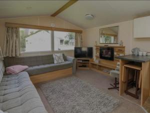 a living room with a couch and a television at Caravan 3 - Blackmoor farm near Tenby in Ludchurch