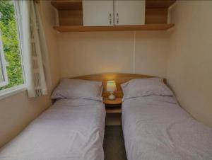 two beds in a small room with a table with a lamp at Caravan 3 - Blackmoor farm near Tenby in Ludchurch