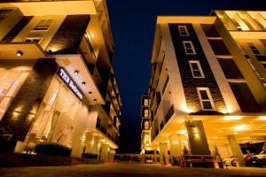 two tall buildings are lit up at night at The Bedroom Ladprao 101 Bangkok - SHA in Bangkok