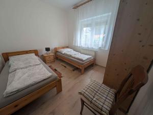 a bedroom with two beds and a chair and a window at Apartment in Zamardi - Balaton 40474 in Zamárdi