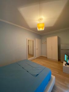 a bedroom with a blue bed and a television at Apartment in Primavera Residence in Fushë-Draç