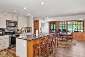 a kitchen with white cabinets and a large island with bar chairs at Serenity Cove Lake House #2472 by Big Bear Vacations in Big Bear Lake