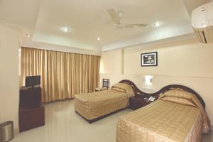 a hotel room with two beds and a television at Hotel Indraprastha Kayamkulam in Pattiyūrgrāmam
