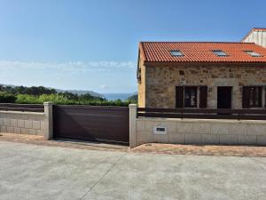 a building with a gate next to a house at A Luz do Faro in Muxia