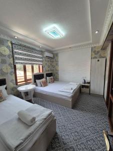 een grote kamer met twee bedden en een wastafel bij HOTELVAZIRA in Samarkand