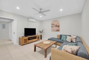 a living room with a couch and a tv at Seascape Solace - Breezy Waterfront Bliss in Palm Cove