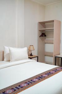 Komodo Labuan Bajo AirportにあるMama Komodo Bed & Breakfastの白いベッドとクローゼットのある寝室