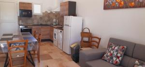 eine Küche mit einem Tisch und einem weißen Kühlschrank in der Unterkunft Gîte Garouille in Saint-Porchaire