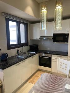 a kitchen with white cabinets and black counter tops at Hawana salalah Forest island L3-G01 in Salalah