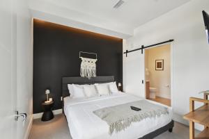 a bedroom with a large white bed with a black wall at Japandi Minimalism | Espadin LoHi in Denver