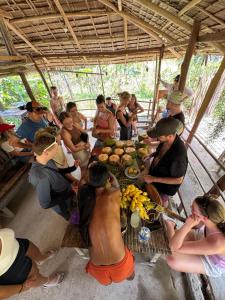 a group of people sitting around a table with food at El Trinidad Organic Farm in El Nido