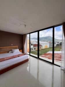 DiyengにあるHome Stay Pandawa Limaのベッドルーム1室(ベッド1台、大きなガラス窓付)