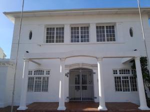 a white building with a gate in front of it at BIM Backpackers In Muizenberg in Muizenberg