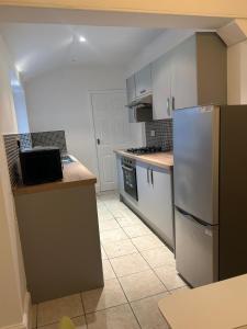 a kitchen with white cabinets and a white refrigerator at Family Contractor Modern Home Sleeps 7 Free parking in Grimsby