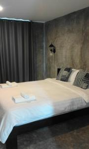 a bedroom with a large bed with two towels on it at Come Moon Loft Hotel in Phrae