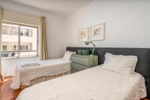 a bedroom with two beds and a window at Rocha Beach Apartment in Praia da Rocha