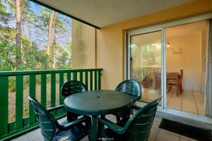 a porch with a table and chairs on a balcony at Appartement entre lac et océan in Carcans