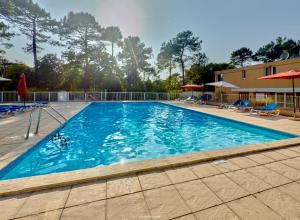 a large swimming pool with blue water at Appartement entre lac et océan in Carcans