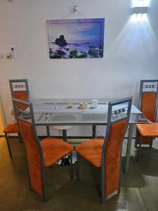 a dining room table with orange chairs and a table and a painting at Kuća za odmor NADA in Legrad