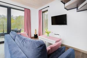 a living room with a blue couch and a tv at Piekny Domek Koralowy w Lubkowie by Renters Prestige in Lubkowo