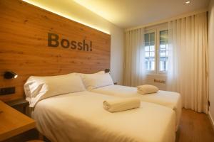 two beds in a hotel room with a sign on the wall at Plaza Obradoiro Express by Bossh! Hotels in Santiago de Compostela