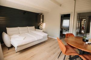 a bedroom with a white bed and a wooden table at Szépasszony Guest House in Vlăhiţa
