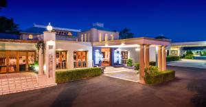 a large white mansion at night with lights at Shangri-La Gardens in Brisbane