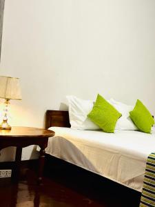 a bedroom with a bed with green pillows and a table at Rose hotel in Bandarawela