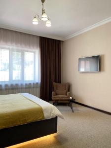 a bedroom with a bed and a chair and a television at Keremet Hotel in Almaty