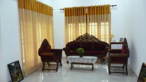 Una sala de estar con un sofá y sillas y una mesa. en Serene Home Stay, en Udawalawe