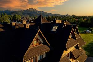 a view of roofs of houses with a mountain in the background at Grand Podhale Resort&Spa Zakopane - Jacuzzi z możliwością rezerwacji na wyłączność - Widok na Tatry in Zakopane