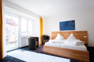 a bedroom with a bed with white pillows and a window at Hotel Capri in Überlingen